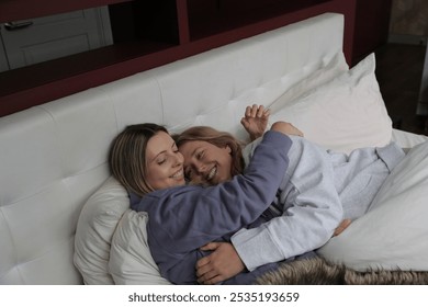 Cheerful lesbian couple embracing in bed - Powered by Shutterstock