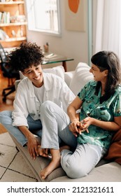 Cheerful Lesbian Couple Laughing Together. Happy Young Lesbian Couple Sharing A Laugh While Relaxing Together In Their Living Room. Young LGBTQ+ Couple Spending Quality Time Together At Home.