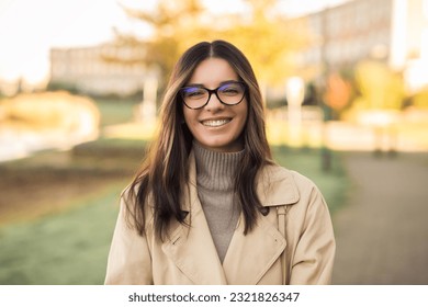 Cheerful LGBT female student wearing glasses joyfully smiling beautifully in front of campus