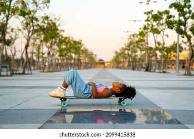 Cheerful Little African Child Girl Kid Skateboarding At Park In The City. Happy Cute Preschool Girl Enjoy And Having Fun Outdoor Lifestyle Practicing Extreme Sport Longboard Skating On Summer Vacation