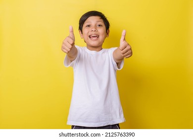 Cheerful little boy raising his two thumbs forward isolated on yellow background