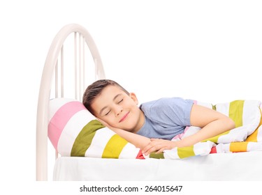 Cheerful little boy sleeping in a comfortable bed and dreaming sweet dreams covered with a blanket isolated on white background