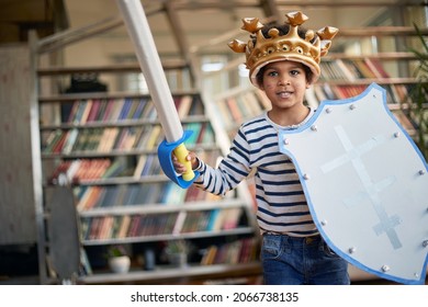 A cheerful little boy with a sword and a shield is posing for a photo while playing in a relaxed atmosphere at home. Family, home, playtime