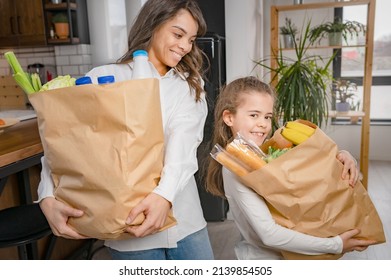 Cheerful Little Daughter Helping The Mother To Carry Groceries From The Market. Household Chores For Kids.