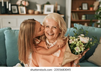 Cheerful little girl giving flowers to grandmother indoors - Powered by Shutterstock