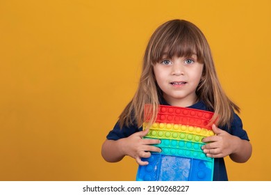 Cheerful little girl plays on a multicolored plastic pop toy .Playing at home during summer vacation - Shutterstock ID 2190268227