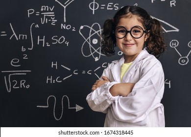 cheerful little girl science student in lab coat on school blackboard background with hand drawings science formula pattern, back to school and successful female career concept - Shutterstock ID 1674318445