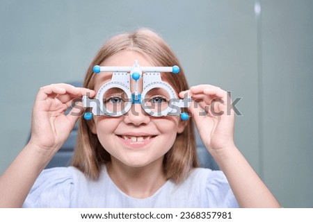 Cheerful little girl undergoing eye exam with refraction test