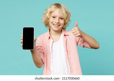 Cheerful Little Kid Boy 10s In Pink Shirt Hold Mobile Cell Phone With Blank Empty Screen Showing Thumb Up Isolated On Blue Turquoise Background Children Studio Portrait. Childhood Lifestyle Concept