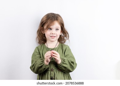 A cheerful little red-haired girl, rolling her eyes, playfully looks up. Studio photo of handsome preschooler child on white background