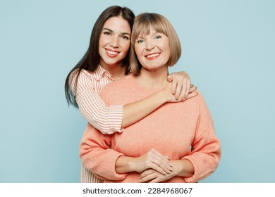 Cheerful lovely fun satisfied elder parent mom with young adult daughter two women together wearing casual clothes hugging cuddle look camera isolated on plain blue cyan background. Family day concept
