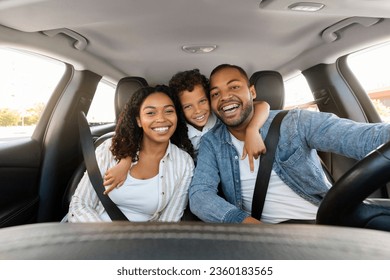 Cheerful loving black family father, mother, preteen kid son posing in car, embracing and smiling at camera. Happy african american parents go vacation by auto with their child, enjoy time together - Powered by Shutterstock