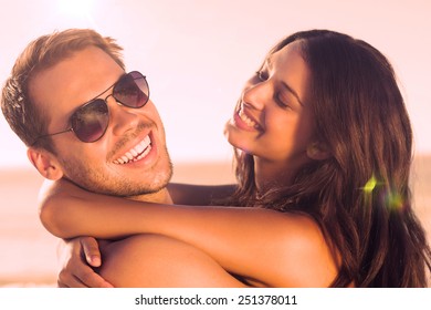 Cheerful loving couple hugging each other on the beach - Shutterstock ID 251378011