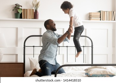 Cheerful Loving Father Having Fun With Cute Little Kid Jumping On Bed, Happy African Family Young Dad And Small Son Playing In Bedroom, Excited Black Parent Child Boy Feel Joy Bonding Enjoy Leisure