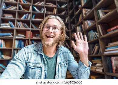 Cheerful male blogger influencer waving hand looking at camera recording video blog concept in library, happy young man laughing face shooting vlog for social media channel making video call concept. - Powered by Shutterstock