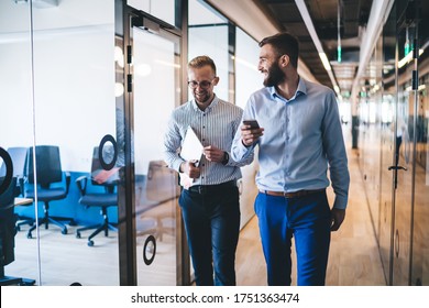 Cheerful male employees working in company hallway and laughing enjoying live communication in friendly working environment, prosperous executive managers with modern technology discussing wireless - Powered by Shutterstock