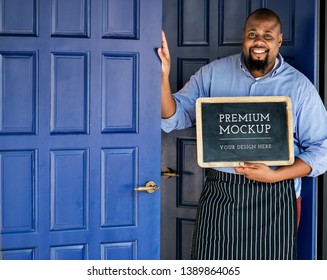 Cheerful male entrepreneur standing with a blackboard mockup