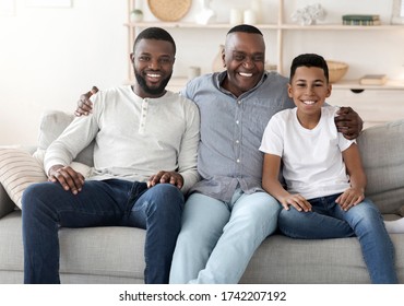 Cheerful Male Family Members Posing To Camera At Home, Embracing On Sofa And Smiling