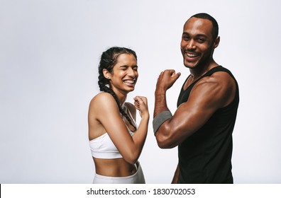 Cheerful male and female athlete standing together and laughing. Fit couple showing muscular arm standing together. - Powered by Shutterstock