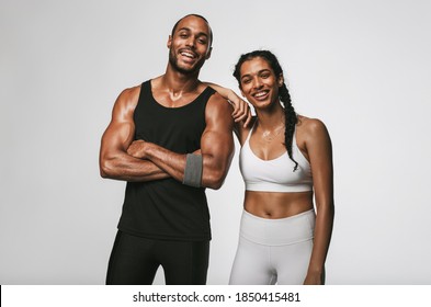 Cheerful male and female athlete standing together at gym. Smiling woman standing with her hand on shoulder of male friend.