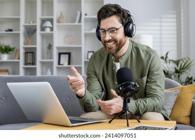 Cheerful male podcaster recording content in a cozy home office, using laptop and professional audio equipment. - Powered by Shutterstock