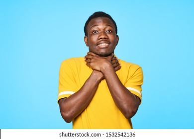 A cheerful man of African appearance holds on to the neck a yellow shirt studio casual wear