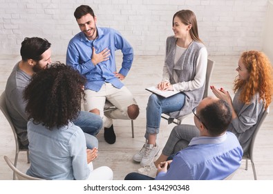 Cheerful man appreciates support of people at rehab group meeting, empty space