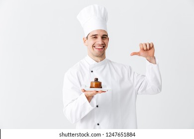 Cheerful Man Chef Cook Wearing Uniform Showing Pastry On A Plate Isolated Over White Background