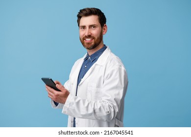 Cheerful Man Doctor Holding Mobile Phone Over Blue Studio Background