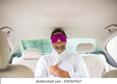 Cheerful Man With Dressing Gown And Eye Mas Sitting In Car, Resting.