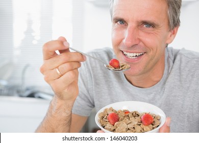 Cheerful Man Eating Cereal For Breakfast Looking At Camera