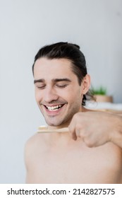 Cheerful Man Holding Toothbrush With Toothpaste In Bathroom