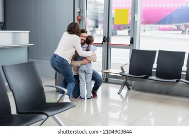 Cheerful Man Hugging Family In Airport