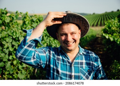 Cheerful Man With Modern Young Winemaker Hat Is On The Vineyard. The Portrait Of The Winemaker Looking At The Camera