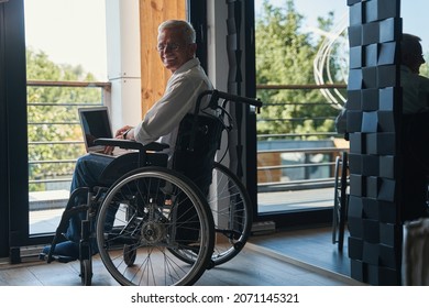 Cheerful Man With Paraplegia Working On Laptop