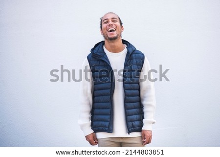 Cheerful man in puffer jacket laughing over white background