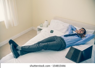 Cheerful man relaxing on his bed in a bedroom at home - Shutterstock ID 154815446