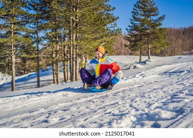 Cheerful Man Sledding Down A Snowy Slope In Full Speed