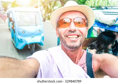 Cheerful man taking travel selfie at Borakay Philippines island with local trycicle taxi background - Happy middle age tourist with enthusiastic facial expression doing self photo into road traffic  - Powered by Shutterstock