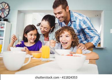 Cheerful man and woman with children during breakfast at home - Powered by Shutterstock