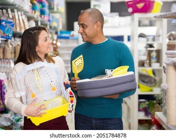 Cheerful man and woman satisfied customers of pet store posing with pet supplies