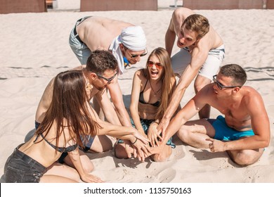 Cheerful mates from european college, guys and girls during their vacation time relaxing on beach volleyball court, sitting in circle, thinking over stategy of game, cherring each other for win. - Powered by Shutterstock