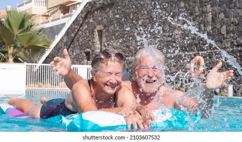 Cheerful Mature Adult Active Happy Senior Couple Of Grandparents Having Fun In The Swimming Pool Floating On Mattress Outdoors In Water. Relaxed Retired People Enjoying Vacation Healthy Lifestyle