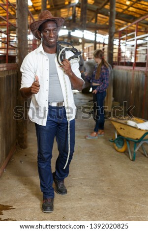 Cheerful mature african man in working clothes posing at stable