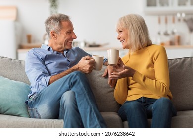 Cheerful Mature Couple Drinking Tea And Talking Sitting On Sofa At Home. Retired Senior Spouses Holding Cups Of Coffee Enjoying Conversation On Weekend. Retirement Lifestyle, Happy Marriage - Shutterstock ID 2076238642