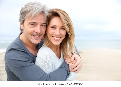 Cheerful mature couple embracing by the beach
