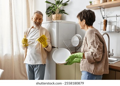 A cheerful mature couple enjoys washing dishes while sharing laughter in their warm kitchen - Powered by Shutterstock