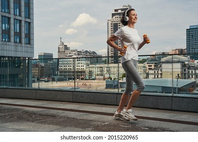 Cheerful Mature Female Going Running With Earphones