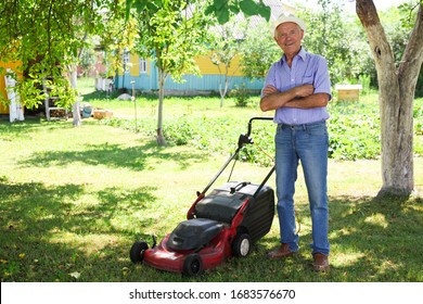 Cheerful mature man with lawnmower on a farm