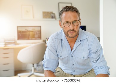 Cheerful mature man sitting in home-office 